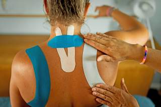 Kinesiotapes werden im Bereich von Nacken und Schulter angebracht.