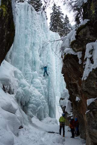 Eisklettern - An einem gefrorenen Wasserfall klettert eine Person im Toprope.