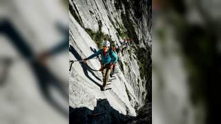 Menschen steigen auf Eisenstiften Klettersteig hinauf