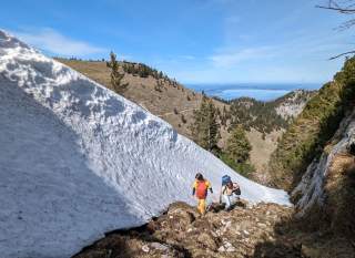 Bergwanderinnen neben einer großen Schneewechte in den Chiemgauer Alpen.