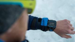 Mann im Schnee schaut auf Uhr