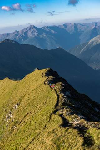 Zwei Menschen wandern auf Grat von Hütte weg