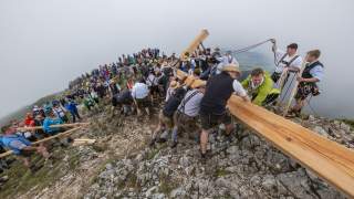 Männer bereiten das neue Kreuz zum Aufstellen am Gipfel der Benediktenwand vor.