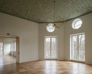Festsaal mit Erker, bemalter, hölzerner Decke und Blick in den Nebenraum.