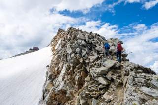Zwei Menschen wandern über Grat zu Hütte