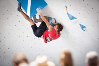 Mann klettert an schwieriger Wand