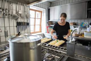 Eine junge Frau in einer Hüttenküche beim Vorbereiten von Gebäck.
