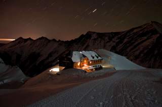 Hütte im Dunkeln an Skipiste, während es schneit