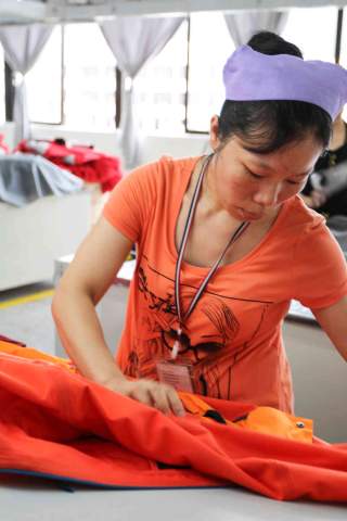 Frau in Fabrik stellt Outdoorjacke her