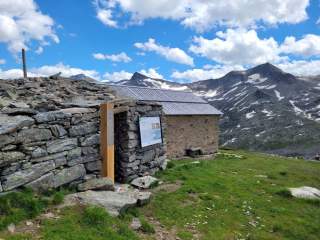 Trockenmauer hinter der Alten Prager Hütte, davor eine Holzstele – die sogenannte 