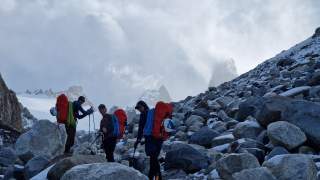 Drei Personen im Blockgelände mit Rucksäcken.