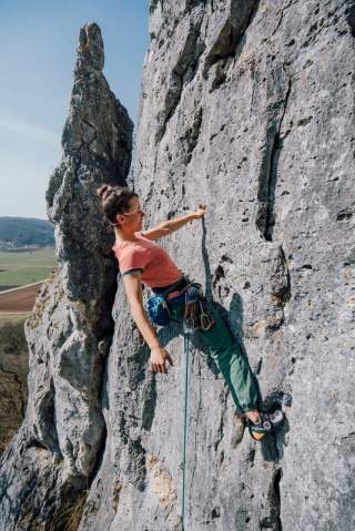 Frau klettert an Felswand