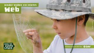 Ein Junge berührt ein Spinnennetz