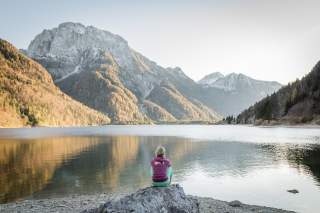 Person sitzt an Bergsee und genießt den Blick Person sitzt an Bergsee und genießt den Blick