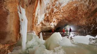 Eis in einer großen, orange-getönten Höhle.