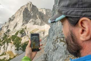Mann mit alpenvereinaktiv-App am Berg