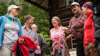 Menschengruppe steht vor Berghütte