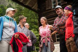 Menschengruppe steht vor Berghütte