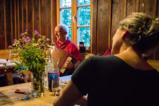 Menschen sitzen in Hütte gemütlich um Tisch