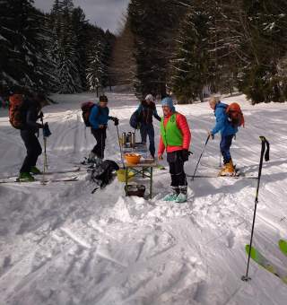 Menschen auf Tourenski machen Pause im Wald mit Tee