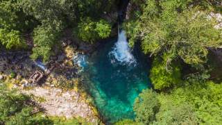 Blick von oben in türkisblaues Wasserbecken, in das Wasserfall fließt