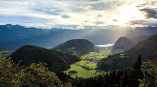 Ausblick über Hügel- und Berglandschaft mit See