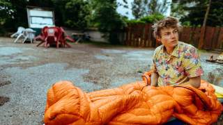 Alex Megos sitzt im Schlafsack
