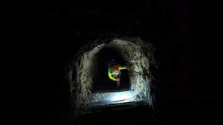 Person mit Helm und Stirnlampe steigt eine dunkle, felsige Treppe in einem Tunnel hinab.