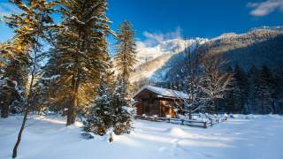 Blick auf eine kleine Hütte, es liegt Schnee, der Himmel ist blau.