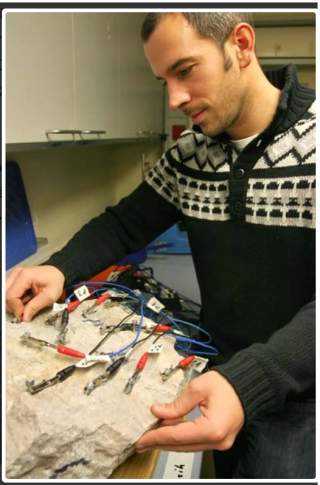 Michael Krautblatter schließt im Labor Messfühler an einer Gesteinsprobe an.