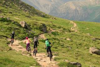 Vier Kinder fahren auf Mountainbikes durch Berglandschaft