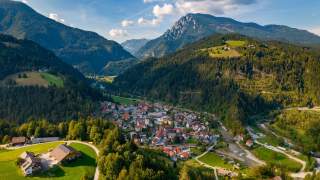 Kleines Dorf umgeben von Hügeln und Bergen im Hintergrund.