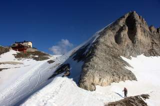 Wanderin in Schneefeld vor Hütte und Fels