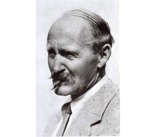 Historisches Porträt eines älteren Mannes mit zurückgekämmtem Haar und Schnurrbart, im Mund eine Zigarre, mit Anzug und Krawatte gekleidet.