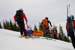 Ein Skifahrer wird mit einem Akja von Bergrettern abtransportiert.