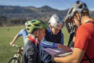Mountainbiker studiert mit Landkarte mit Jugendlichen
