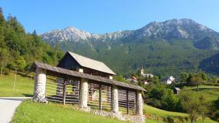 Der Ortseingang eines slowenischen Bergdorfs. Im Hintergrund hohe Gipfel.