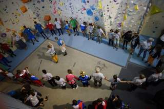 Blick von oben in die Kletterhalle, alle Menschen halten sich an der Hand.