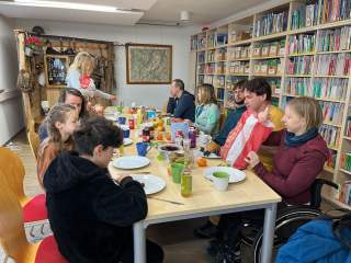 Gruppe von Menschen sitzen an einer gedeckten Frühstückstafel in der Bibliothek der Kletterhalle