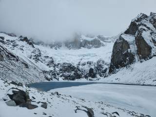 Verschneite Berge, Nebel, gefronerer See