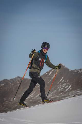 Skibergsteiger beim Aufstieg mit Ski auf Schnee, mit Bergen im Hintergrund