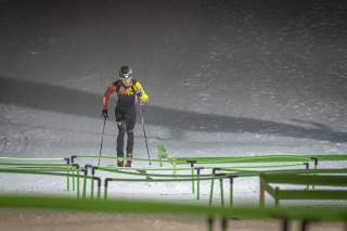 Skibergsteiger bei einem Sprint-Wettkampf unter Flutlicht läuft eine Piste hoch.