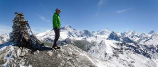 Wanderer steht auf Gipfel mit Ausblick auf Viertausender
