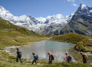 Wandernde vor Bergsee und Gipfelmeer