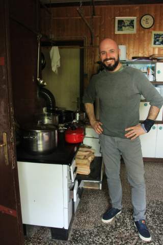 Mann steht in Hütte vor Ofen
