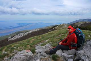 Mann sitzt auf Felsen und blickt aufs Meer und zur Insel Pag