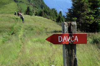 Wegweiser in Wiesengelände mit Wandergruppe