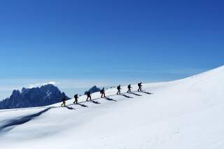 Gruppe von Skitourengehenden vor blauem Himmel