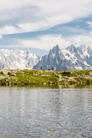 Familie wandert an Bergsee vor Bergmassiv