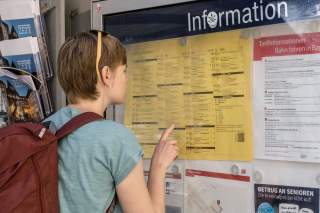 Frau studiert Fahrplan an Bahninformation Frau studiert Fahrplan an Bahninformation